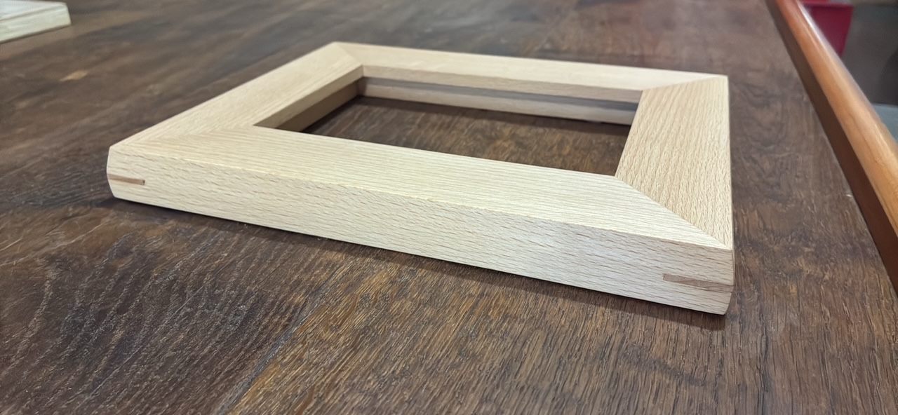 Close view of a pale hardwood frame showing contrasting wooden splines reinforcing the mitered corners.